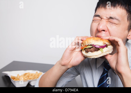 Young businessman enjoying a burger Stock Photo