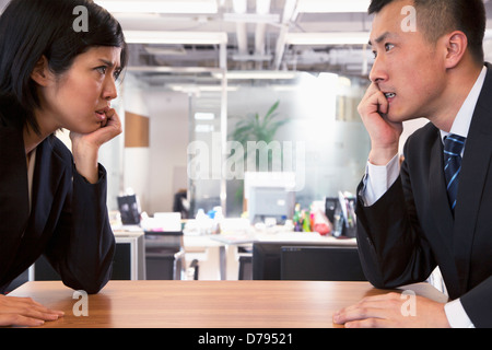 Two Business people staring at each other across a table Stock Photo