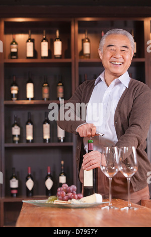 Senior Man Opening Wine Bottle Stock Photo