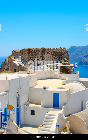 Beautiful empty street and traditional architecture on island of Santorini in Oia, Greece. Ruins and Aegean sea in a background.