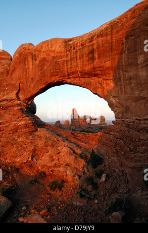 Turret Arch glow glowing red at sunrise viewed through North Window Arch Arches National Park Utah United States sandstone Stock Photo