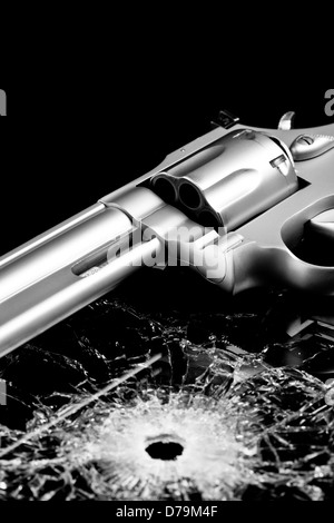 handgun with bullet hole in glass isolated on black - modern revolver with broken glass Stock Photo