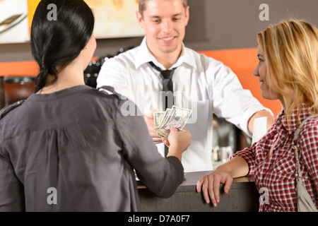 Female customers paying by cash dollar in bar to bartender Stock Photo