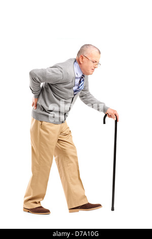 Full length portrait of a senior gentleman walking with cane and suffering from back pain isolated on white background Stock Photo