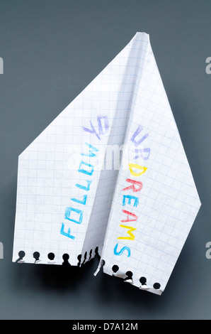 paper plane with Follow your dreams phrase on dark gray background Stock Photo