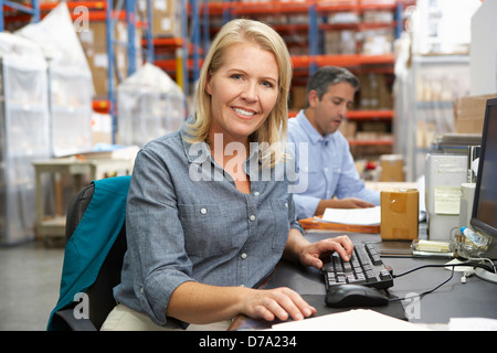 Businesswoman Working At Desk In Warehouse Stock Photo