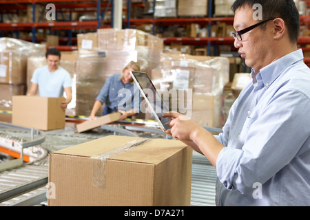 Worker Using Tablet Computer In Distribution Warehouse Stock Photo