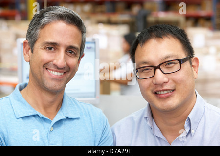 Two Men At Computer Terminal In Distribution Warehouse Stock Photo