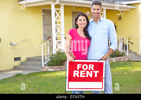 Couple Standing By For Rent Sign Outside Home Stock Photo