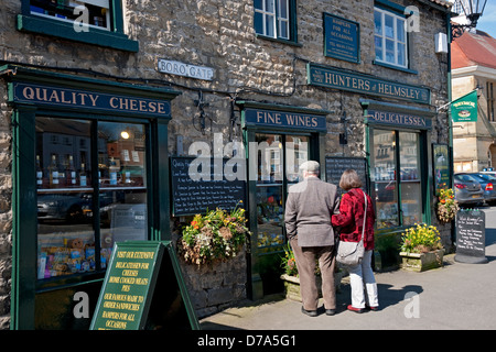 Senior couple people looking in a grocery shop store window in spring Market Place Helmsley North Yorkshire England UK United Kingdom Great Britain Stock Photo
