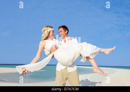 Groom Carrying Bride At Beautiful Beach Wedding Stock Photo