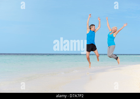 Senior Couple Jumping On Beautiful Beach Stock Photo