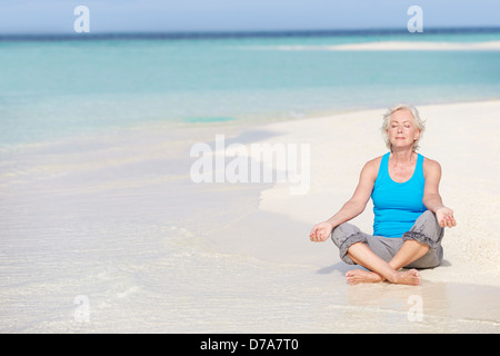 Senior Woman Meditating On Beautiful Beach Stock Photo