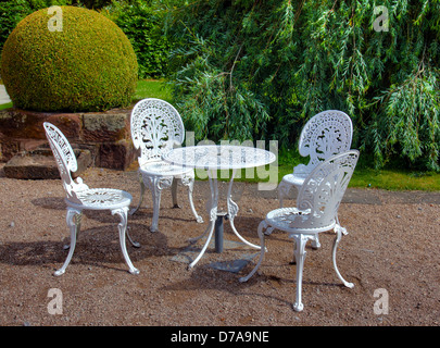 Wrought iron table and six chairs in an English garden. Stock Photo