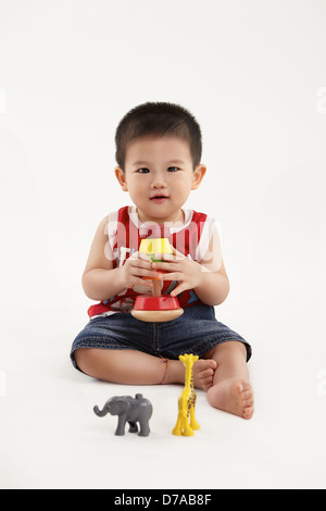 A young kid is happily playing with his colorful blocks and toys Stock Photo