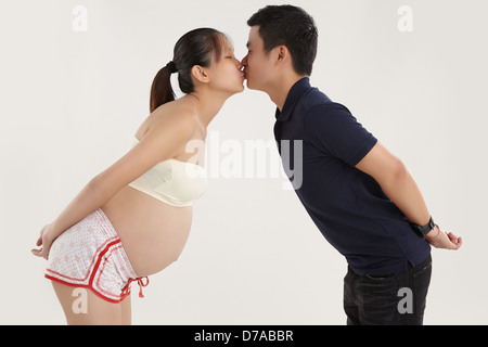A young husband is kissing his pregnant wife Stock Photo