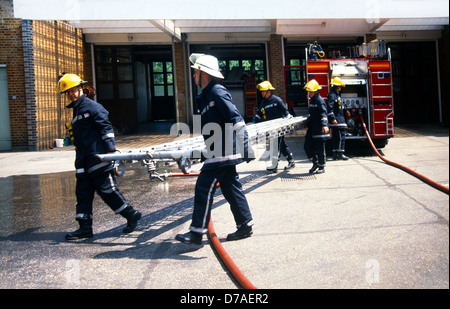 Firemen Carrying Ladder Training Outside Fire Station England Stock Photo