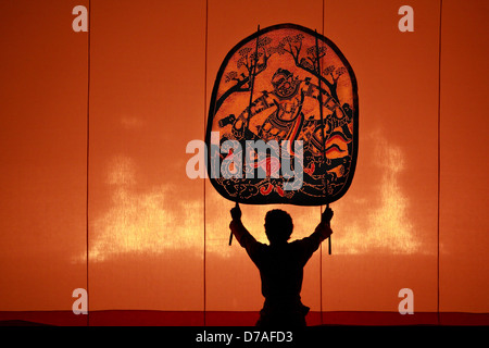 The ancient performing art involves manipulating puppets of cowhide in front of a backlit white screen Stock Photo