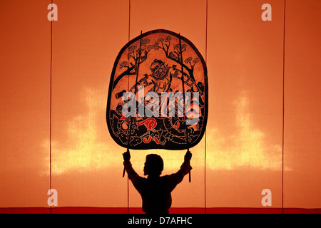 The ancient performing art involves manipulating puppets of cowhide in front of a backlit white screen Stock Photo