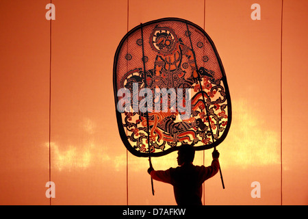 The ancient performing art involves manipulating puppets of cowhide in front of a backlit white screen Stock Photo