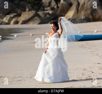 Bride in traditional full white wedding dress with veil on seashore at Pansea Beach, Surin Beach, Phuket, Thailand Stock Photo