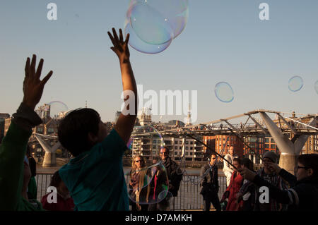 London, England UK 2nd May 2013. Street entertainers blow giant bubbles on the South Bank of the river Thames. Credit:  Patricia Phillips / Alamy Live News Stock Photo