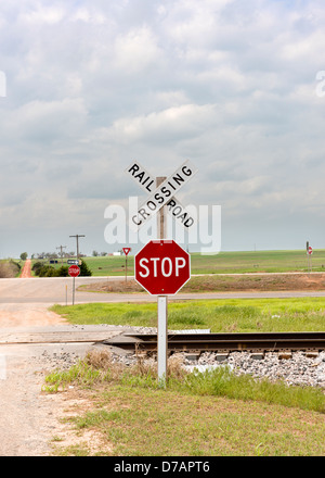 A stop sign and railroad crossing sign next to the railroad tracks with ...