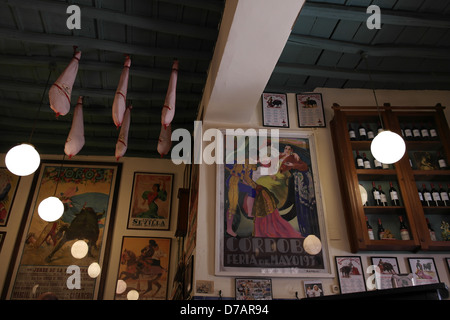 Inside a small traditional bar in the back streets of Seville, with bullfighting posters and iberian ham hanging from rafters Stock Photo