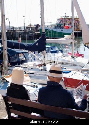 Old couple sat at Padstow Harbour reading a newspaper, UK 2013 Stock Photo