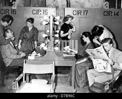 German actors Johannes Heesters (l, sitting), Johanna Matz (l, standing), and Hardy Krüger (r, reading) in the make-up room of a film studio in Hollywood. US actress Maggie McNamara sitting on the right of the table. They are shooting the film 'The Moon is Blue'. Stock Photo