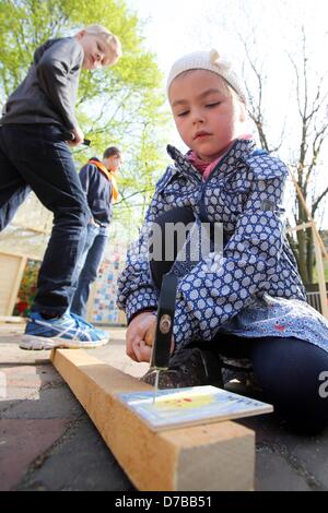 Five-year-old Maya hammers nails into a piece of wood covered with pictures of children during a building project of a children's cathedral in Hamburg, Germany, 03 May 2013. More than 100.000 participants are expected to attend the congress. Photo: BODO MARKS Stock Photo