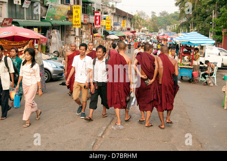 Buddhist monks and locals mix on the streets leading up to the Shwedagon Pagoda Yangon Myanmar (Burma) Stock Photo