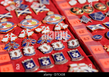 Loyalist/Unionist badges on sale at a market stall beside an Orange Order parade Stock Photo