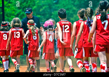 Young girls and coach at the end of a softball game giving congratulations. Stock Photo