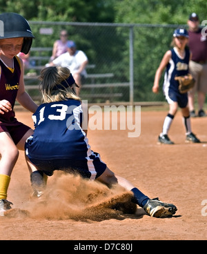 Young girl making a play on base during a softball game. Stock Photo