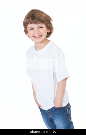 White background studio photograph of young happy boy smiling wearing blue denim jeans hands in pockets Stock Photo