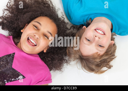 Overhead photograph of two children, blond boy and mixed race African American girl, having fun laying down and laughing Stock Photo