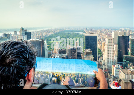 A tourist compares his map to the spectacular view of Central Park in New York City from Top of The Rock, Rockefeller Centre Observation Deck. Stock Photo