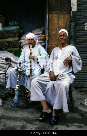 Egyptians wearing traditional Galabyeh garment and smoking Hookah pipe in Khan el-Khalili a major souk in the historic center of Islamic Cairo Egypt Stock Photo