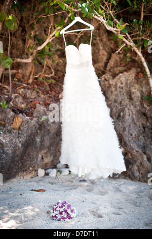 White Wedding dress hanging on a shoulders, outside on beach Stock Photo