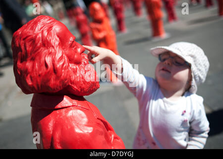 A small girl touches a Karl Marx figure by conceptual artist Ottmaer Hoerl in front of Porta Nigra in Trier, Germany, 05 May 2013. The open air installation of the plastic figures commemorates the birthday of philosopher Karl marx in his place of birth. Photo: OLIVER DIETZE Stock Photo