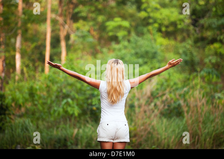 harmony with nature, back woman with raised hands in the forest Stock Photo