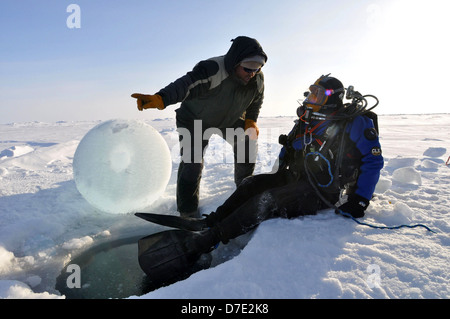 Paul Aguilar, of the University of Washington Applied Physics Laboratory works with Pete Pehl, a member of the Applied Physics Laboratory dive team to recover a torpedo from under the ice while participating with the US Navy Los Angeles-class nuclear attack submarine USS Annapolis in Ice Exercise March 21, 2009 in the Arctic Ocean. Stock Photo