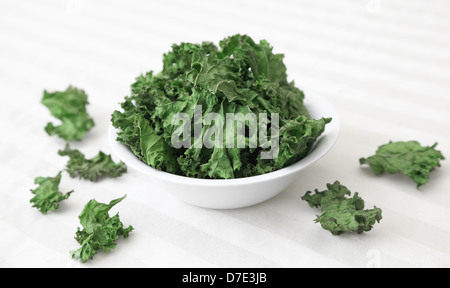 A bowl of home-made kale chips sitting on a table.