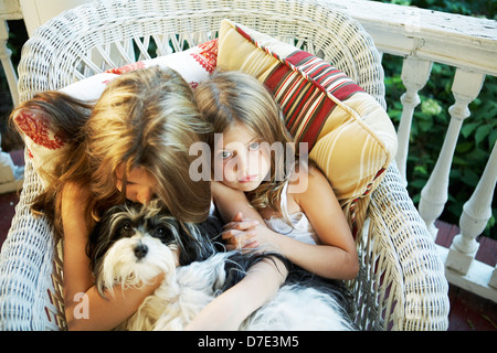 Sisters snuggled up on chair on the front porch Stock Photo