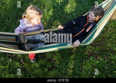 Two children blond girls resting in hammock summer time Stock Photo