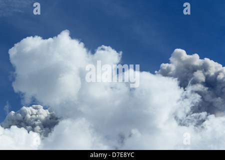 A close-up view of large, puffy white cumulus clouds with textured, billowing formations against a vibrant deep blue sky. The clouds show varying shades of white and gray, with some darker, shadowed Stock Photo