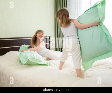 two girls playing with pillows in bedroom Stock Photo