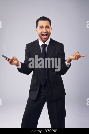 Cheerful young professional holding a phone while gesturing Stock Photo