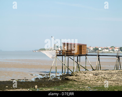 A fisherman repairs his net in a Carrelet fishing hut on stilts on the beach at Fouras, Charente-Maritime, France Stock Photo